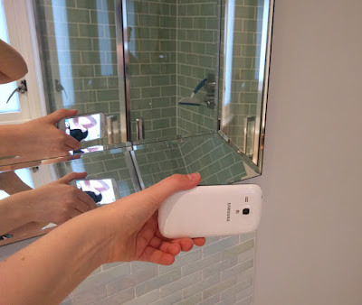 Someone holding a phone up to a mirror such that the viewfinder is visible in the reflection and the back camera is facing the person